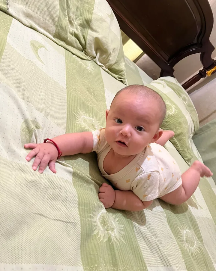 Ian Rafael, de cinco meses, boca abajo sobre la cama, mirando a la cámara.